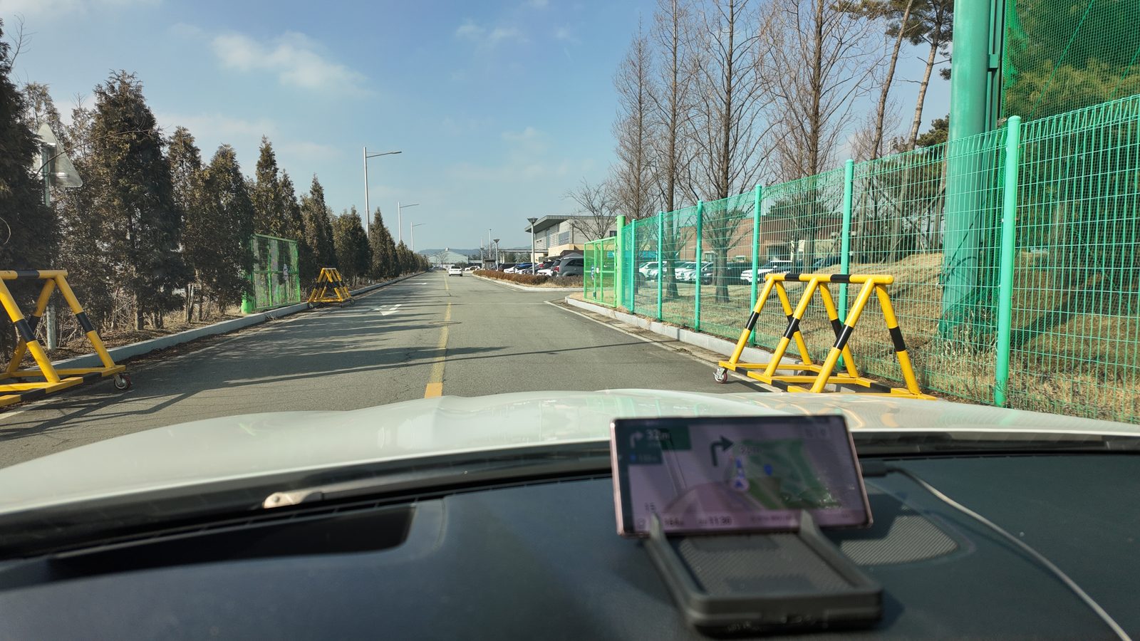녹색 그물 울타리를 따라 이어지는 진입 도로