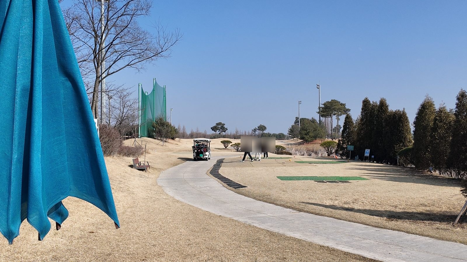 접힌 파란 파라솔과 티잉 구역으로 이어지는 카트 도로